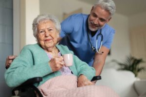 Three seniors sitting together in a bright common room, talking with a staff member who is listening attentively.